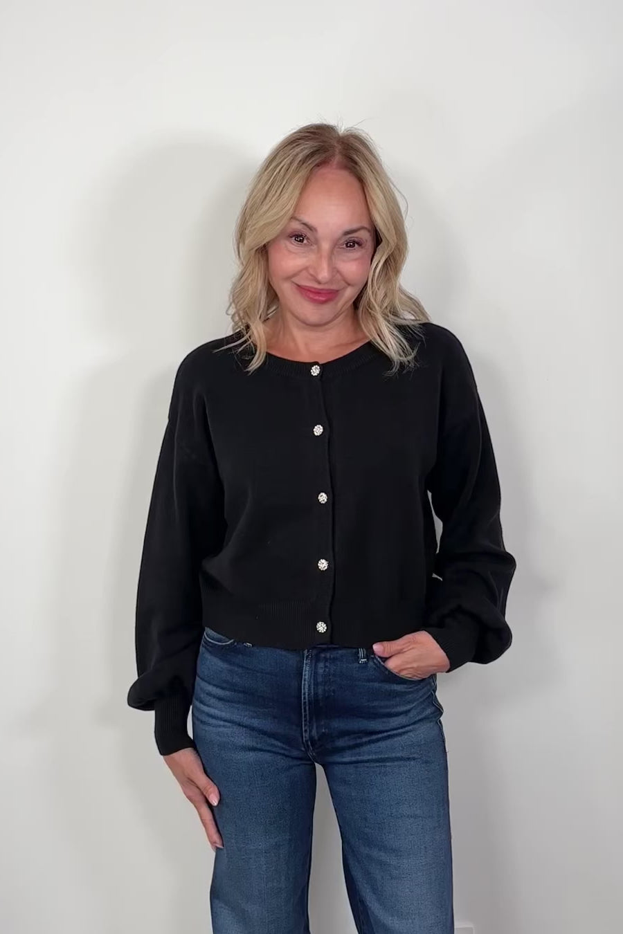Video of a woman wearing a black button up cardigan with crystal buttons