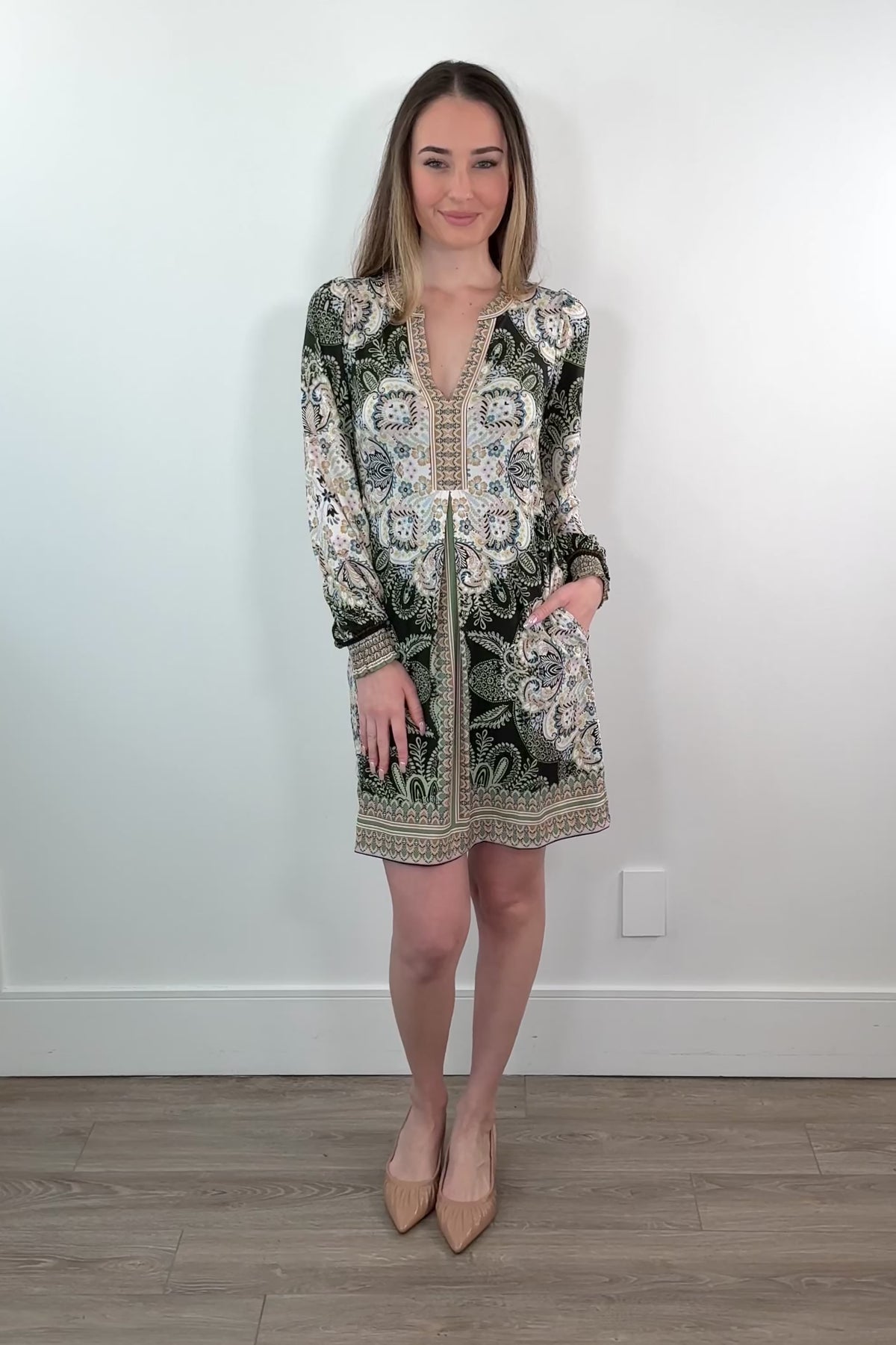 video of a woman wearing an ivory, green and black short long sleeve dress