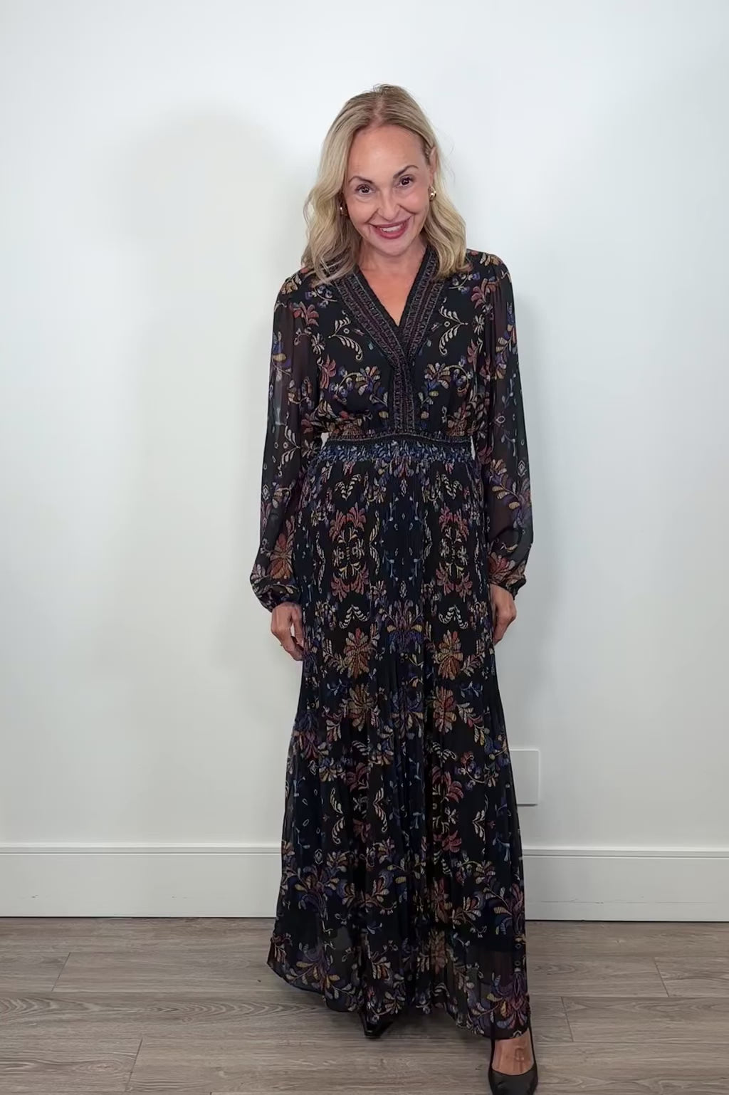 Video of woman wearing a black v-neck maxi dress with a colourful pattern
