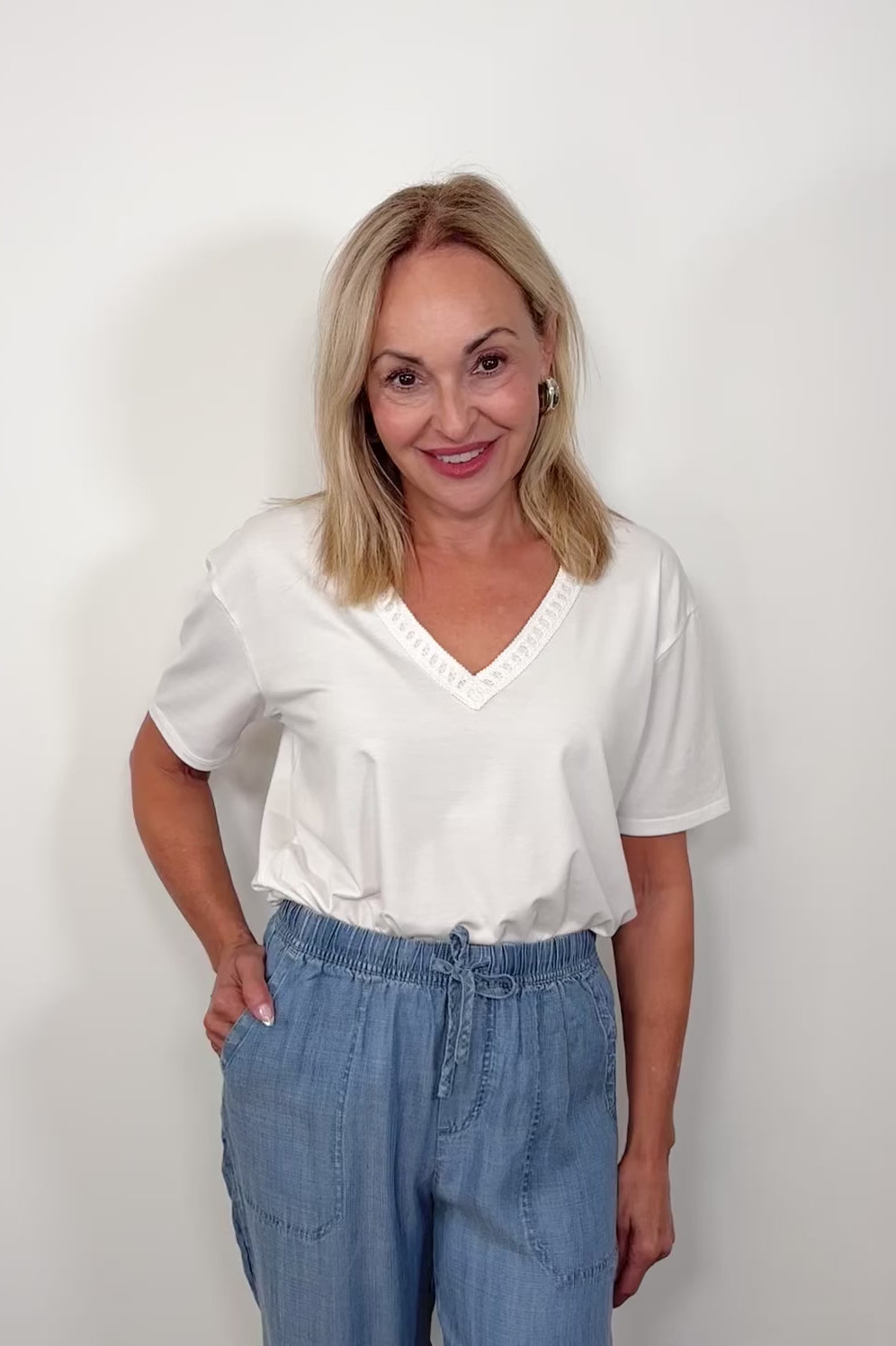 Video of woman wearing a white v-neck tee with detailing on the neck