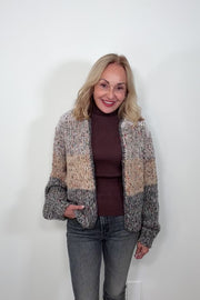 Video of woman wearing a light gray, beige and dark gray knitted cardigan