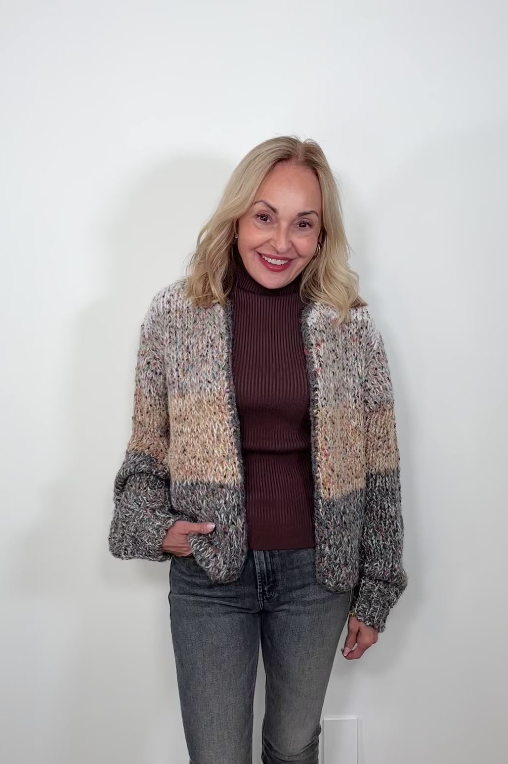 Video of woman wearing a light gray, beige and dark gray knitted cardigan