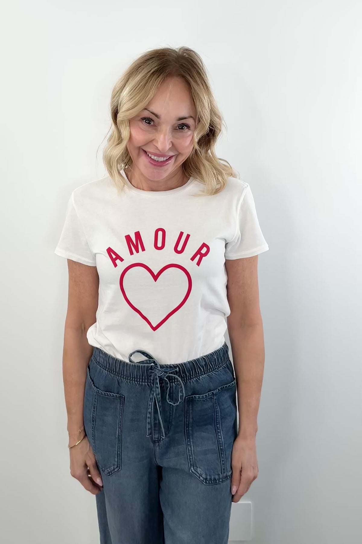 video of woman wearing a white short sleeve tee shirt with the word "amour" and a heart in red on the front