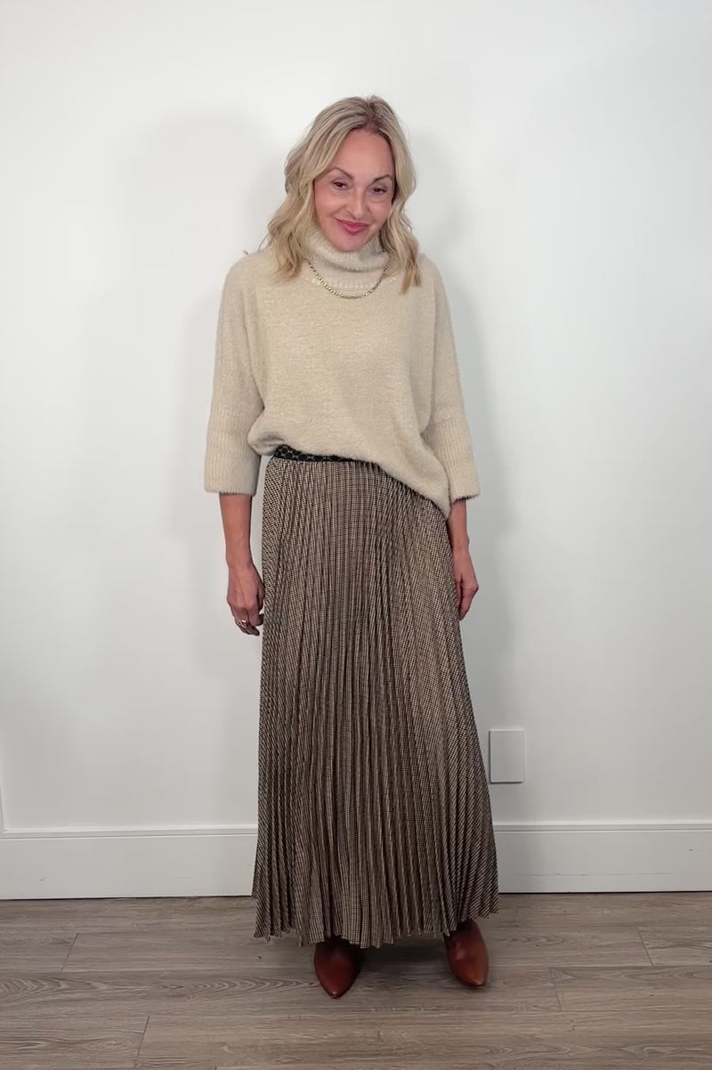 Video of a person wearing a long pleated skirt with a neutral background