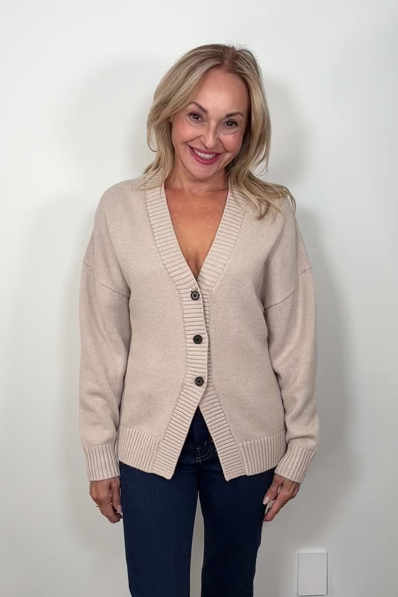 Video of a woman wearing a fitted 3 button beige knitted cardigan