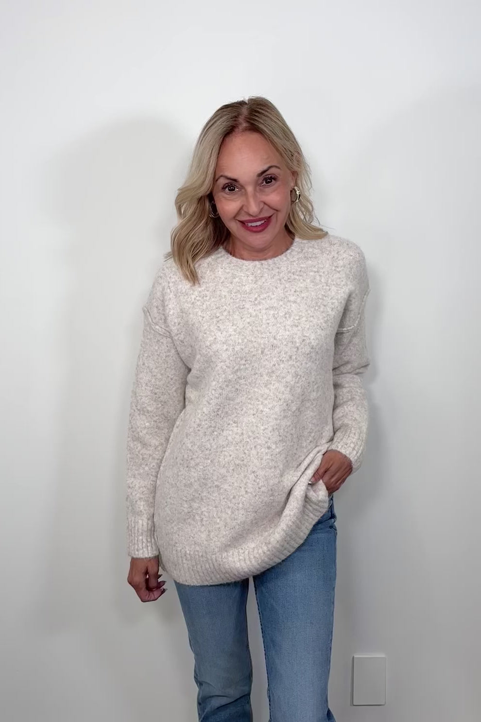 Video of woman wearing an oatmeal coloured oversized knit sweater