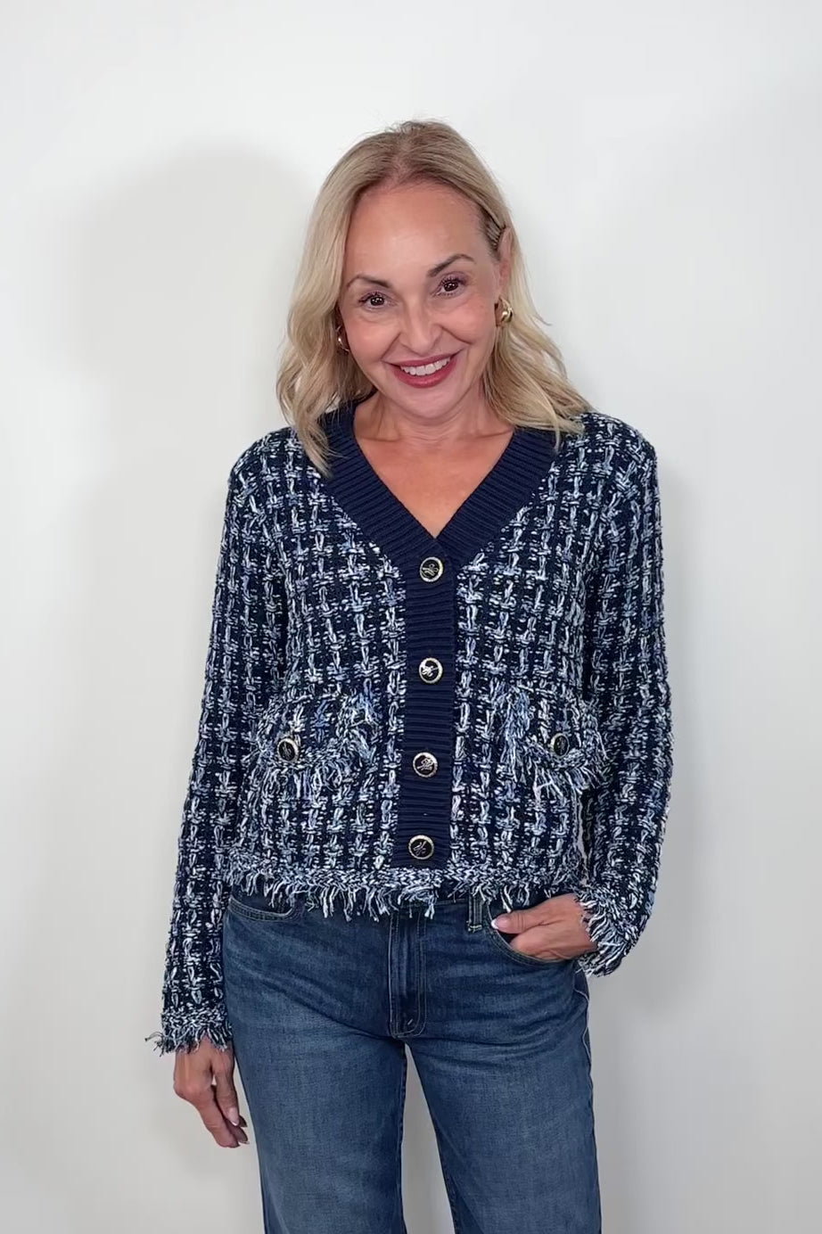 Video of woman wearing a knit blue jacket with ornamental buttons