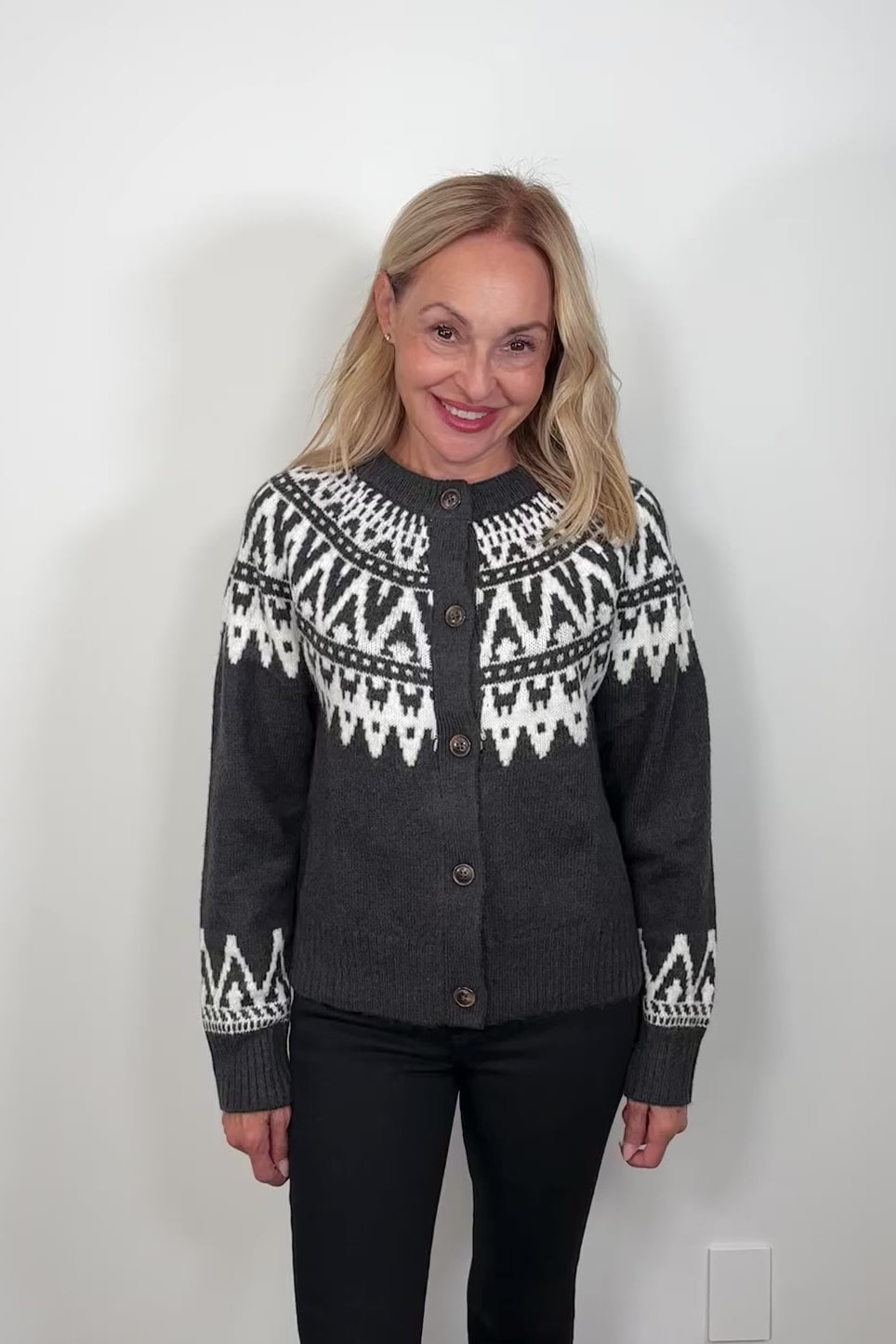 video of a woman wearing a dark gray button up cardigan with detailing on the op and cuffs