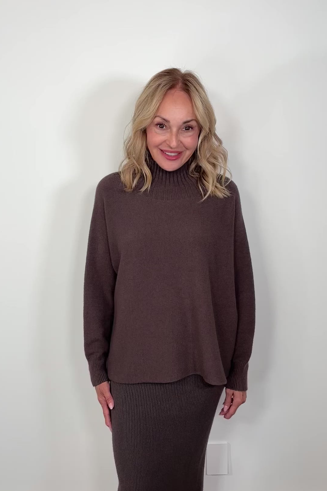 video of a woman wearing a brown oversized mock neck sweater