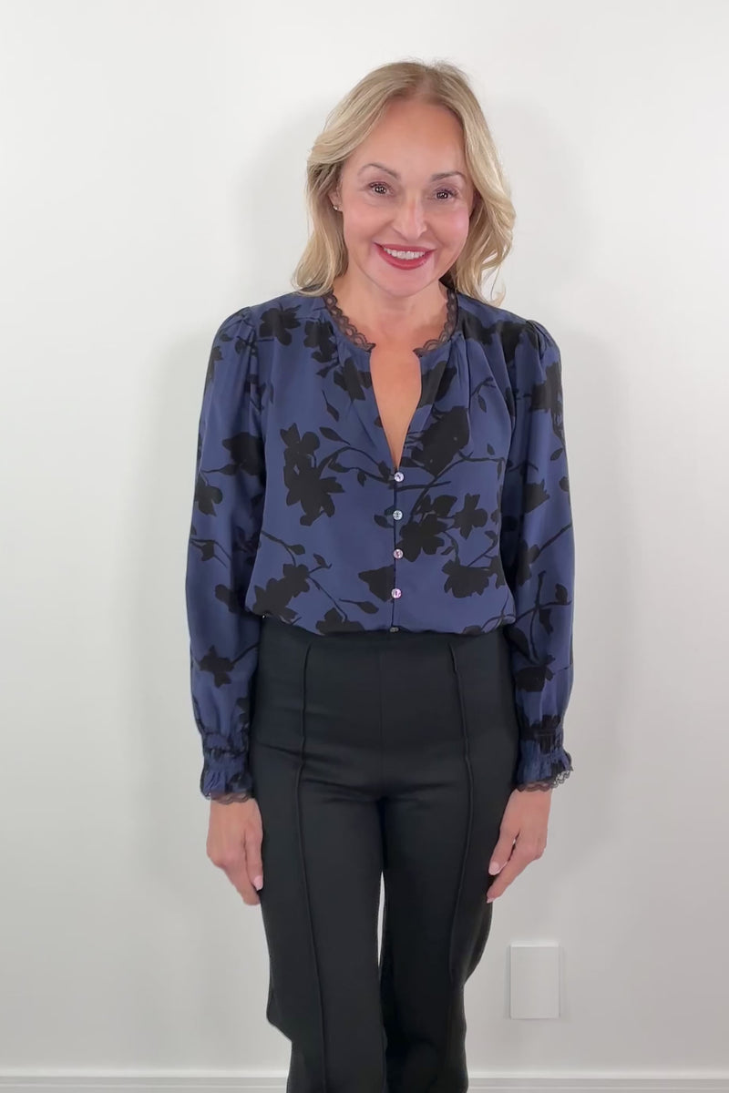 video of a woman wearing a blue floral blouse with lace trim