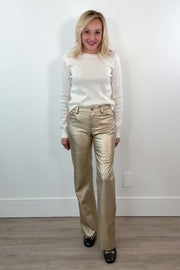 video of woman wearing gold metallic pants against a white wall.