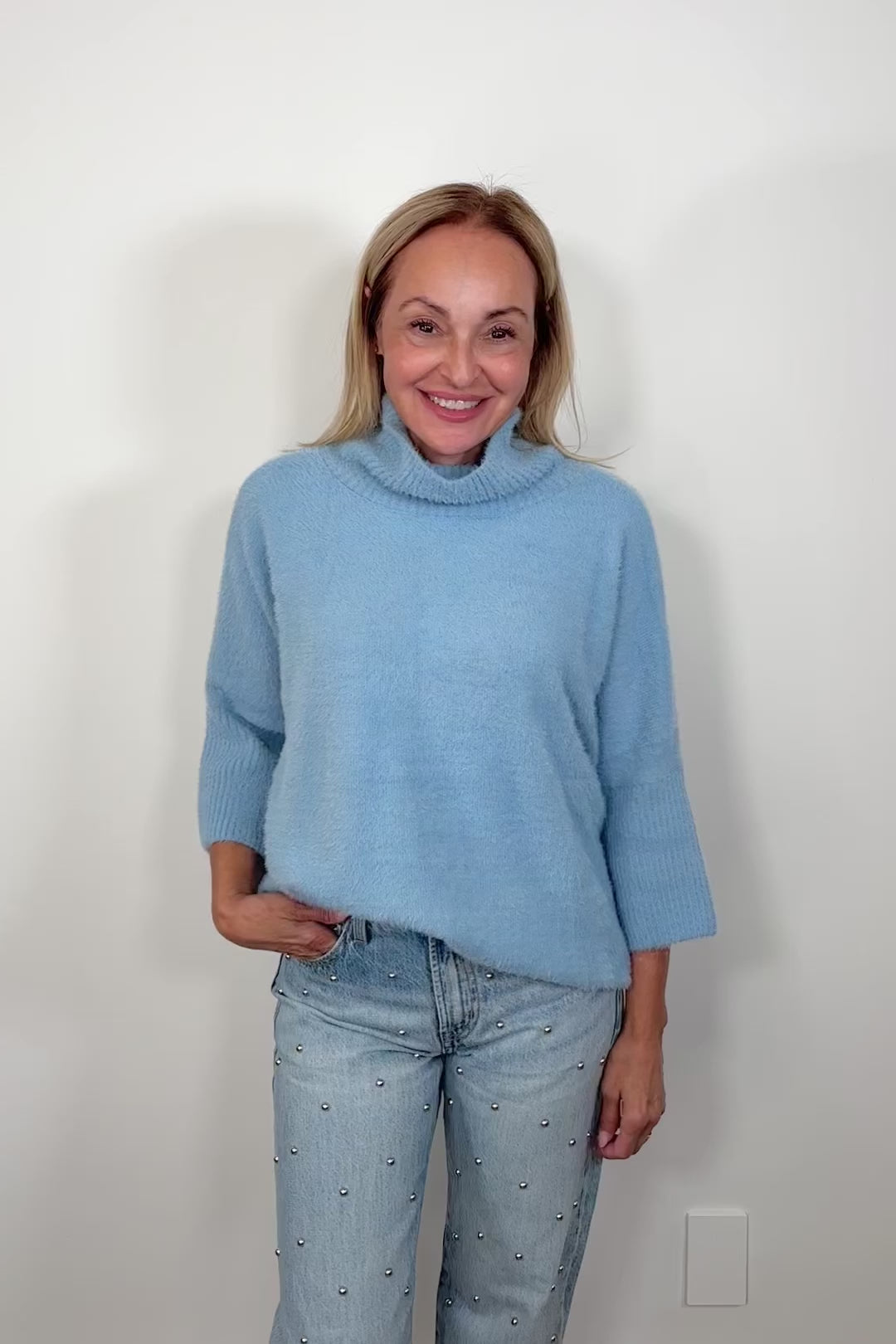 Video woman wearing a blue mock neck 3/4 sleeve sweater top