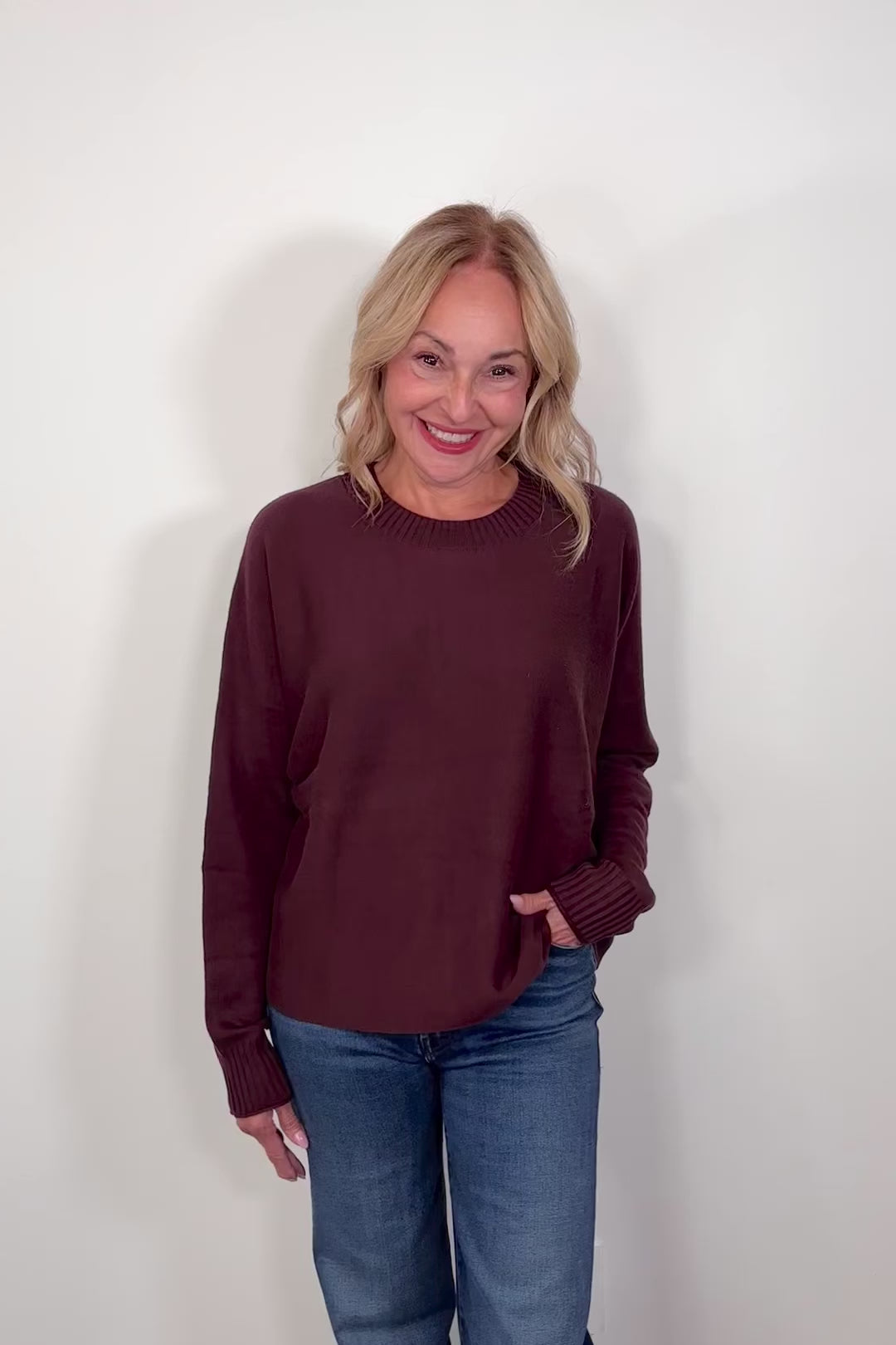 Video of a woman wearing a burgundy crewneck sweater