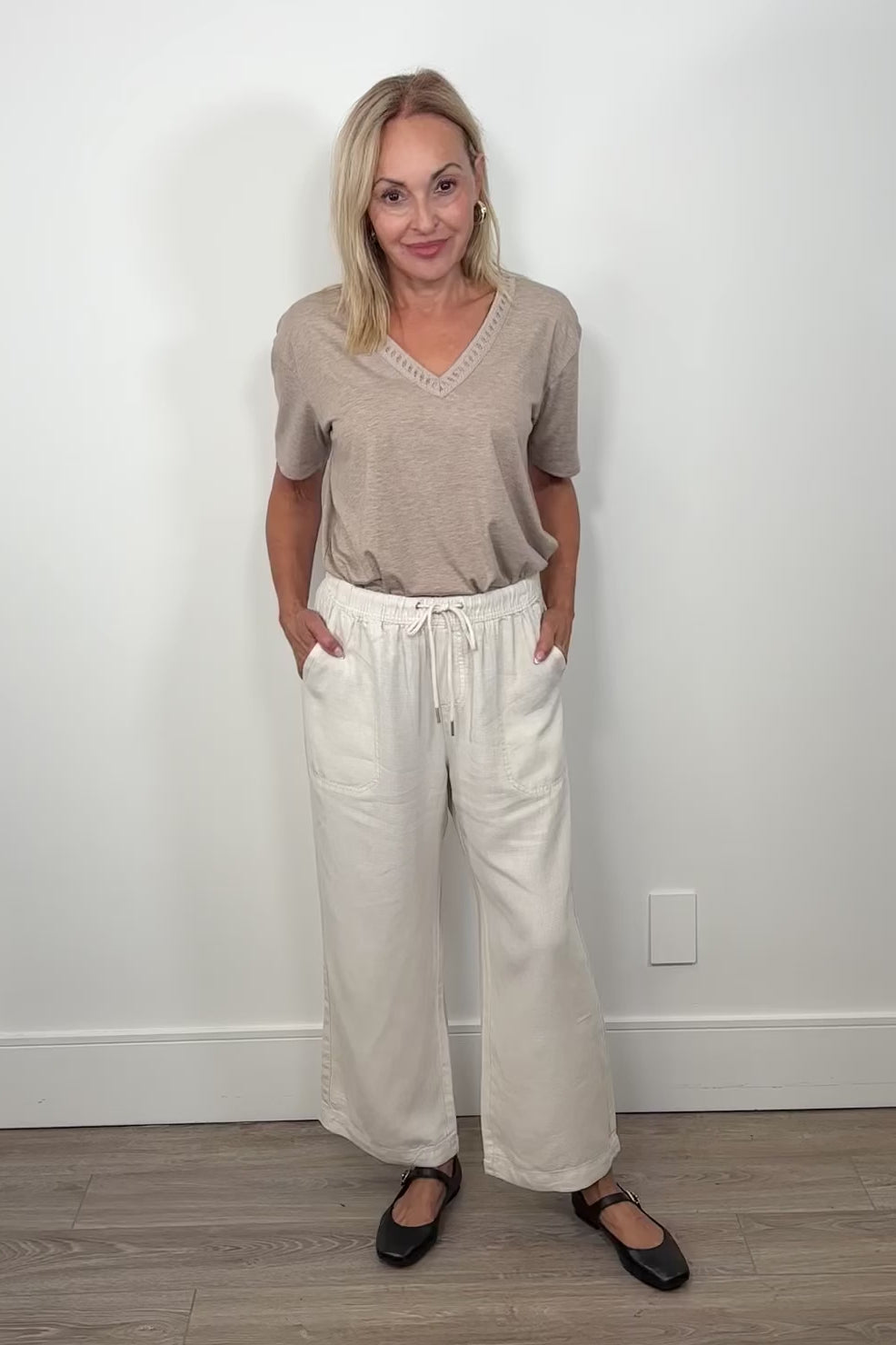 Video of woman wearing cropped light weight white pants with a beige tee