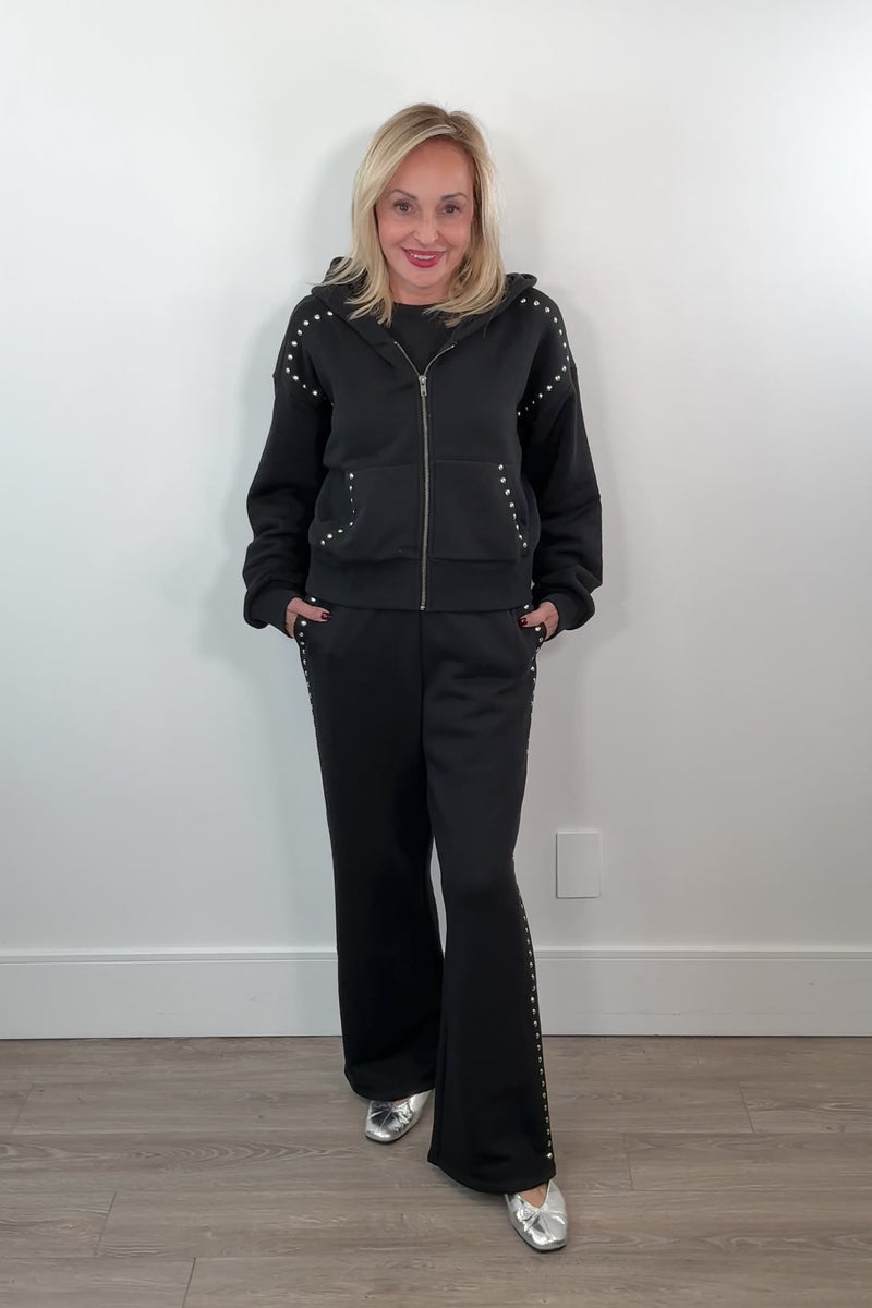 video of a woman wearing matching zip-up and black pants with studded side panels