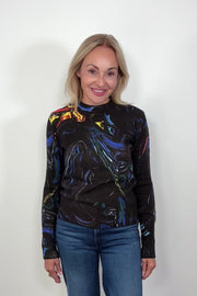 Woman wearing a black long-sleeve sweater with colorful abstract design against a white background