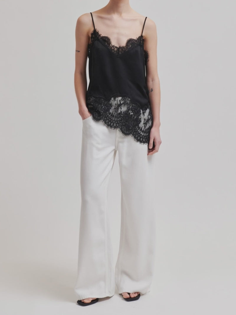 Woman wearing a asymmetrical black lace-trimmed top 