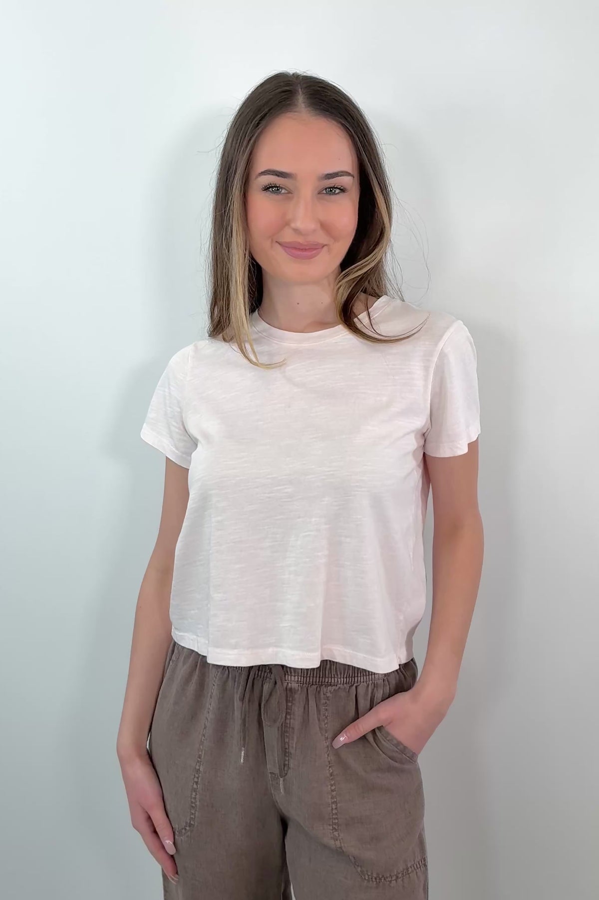 video of a woman wearing light pink tee