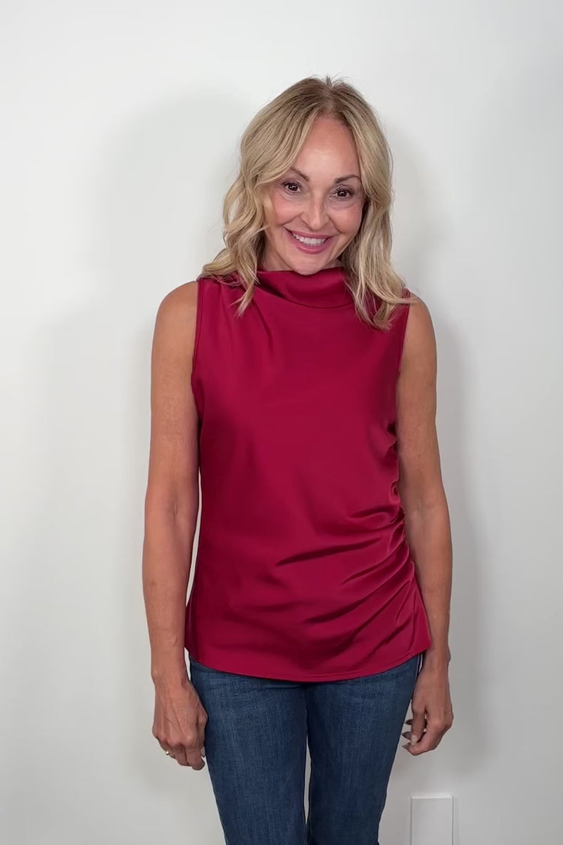 Video of a woman wearing a red rouched sleeveless top turning around to show the back