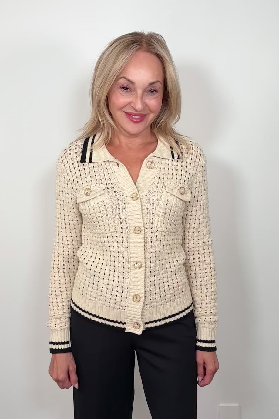 Video of a woman wearing an off white melange knit cardigan with black trim 