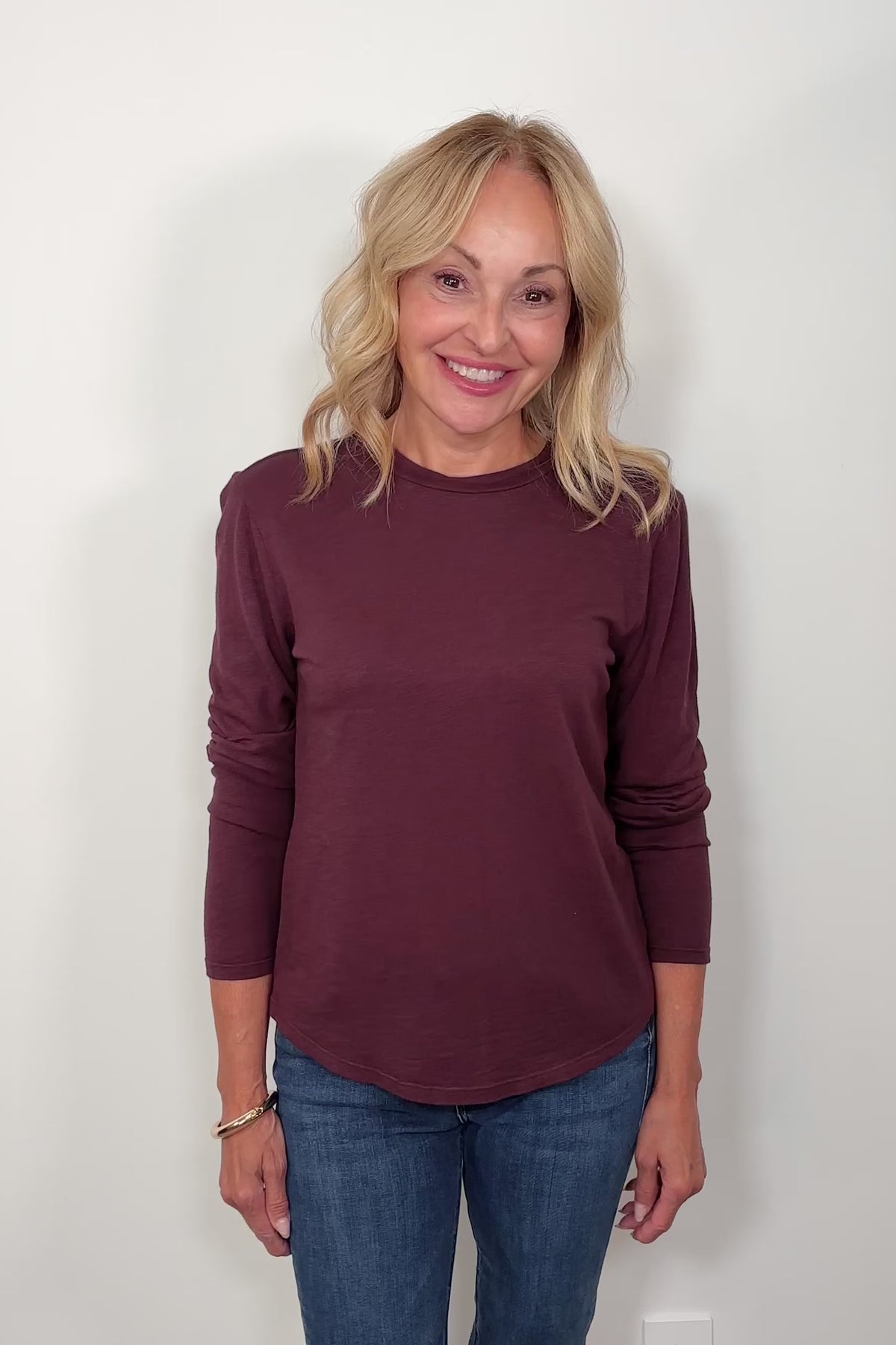 Video of woman wearing a burgundy long sleeve crew neck tee