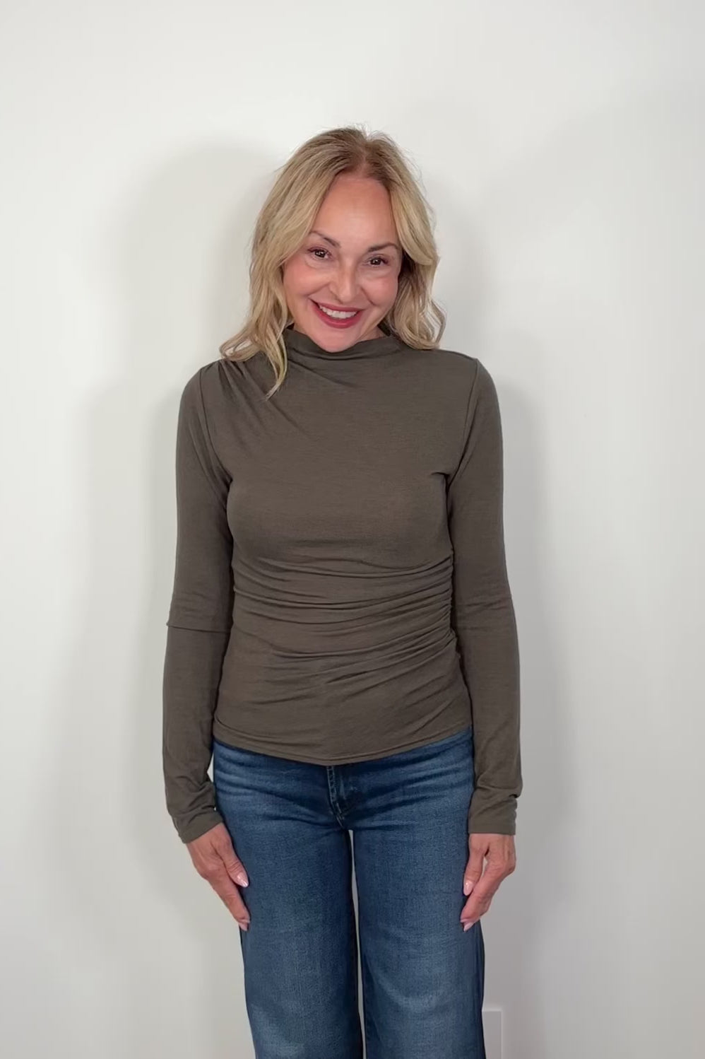 Video of a woman wearing a mock neck rouched long sleeve top