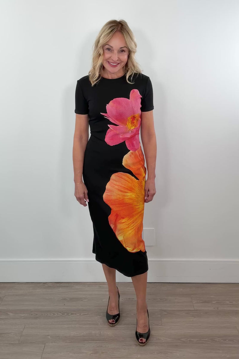 Video of a woman wearing a midi black dress with a two flower print