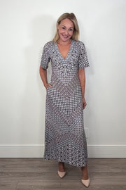 Video of a woman wearing a black and blue pattern jersey midi dress turning around to show the back 