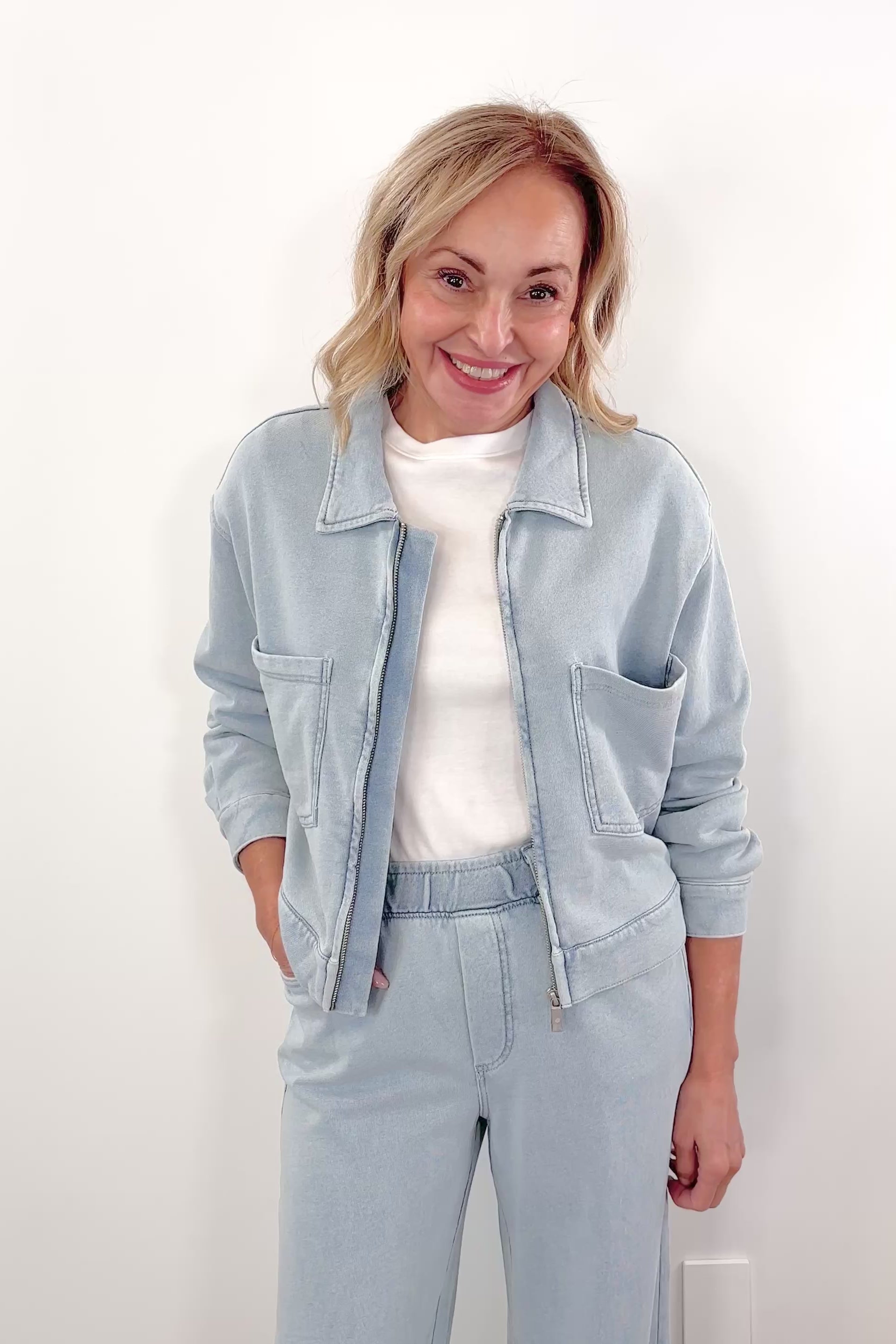 Video of Woman wearing a light blue denim zip front jacket with chest pockets