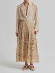 Woman wearing a beige midi skirt with embroidery details and concealed side pockets