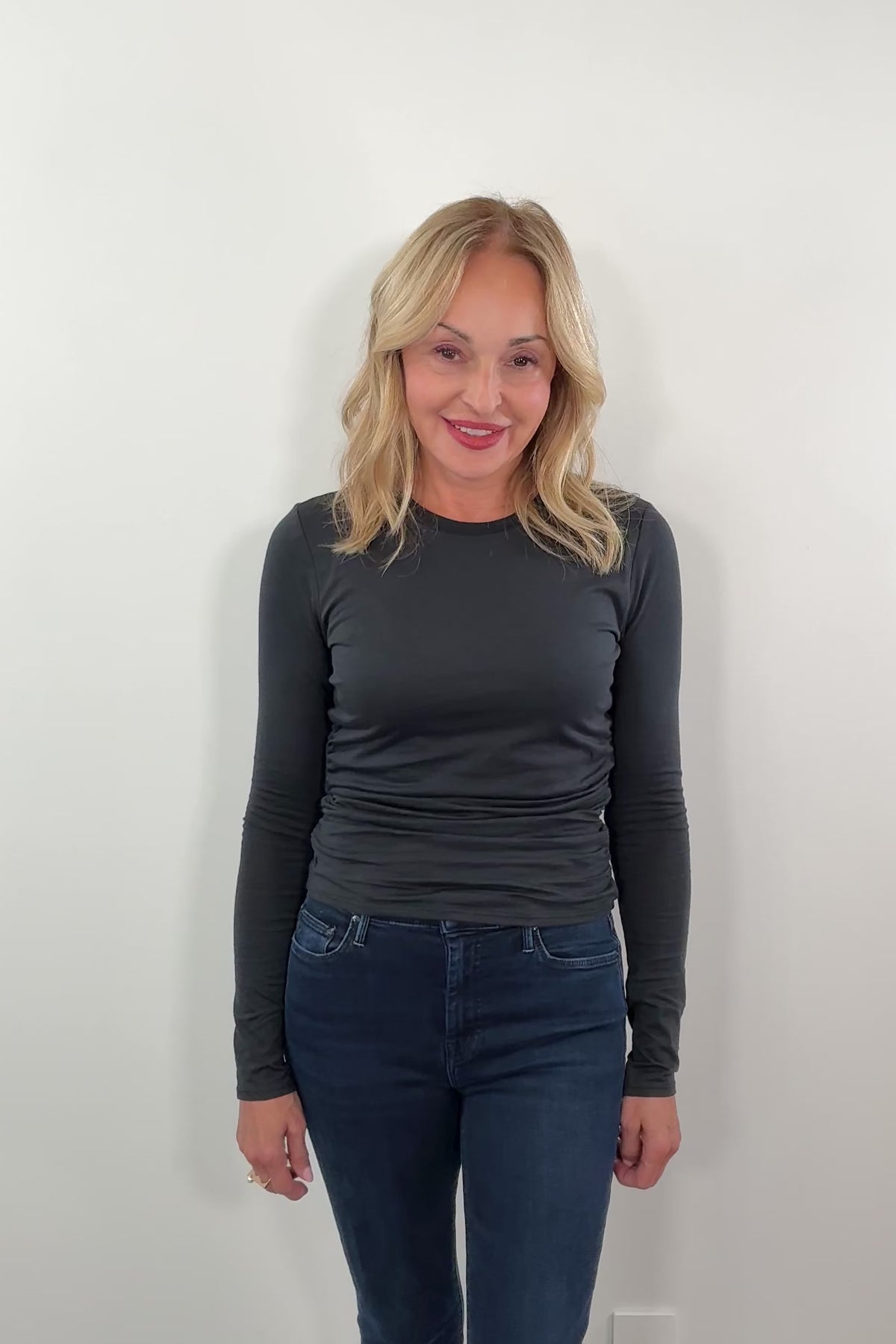 woman wearing a long sleeve black top with ruched detailing on the side