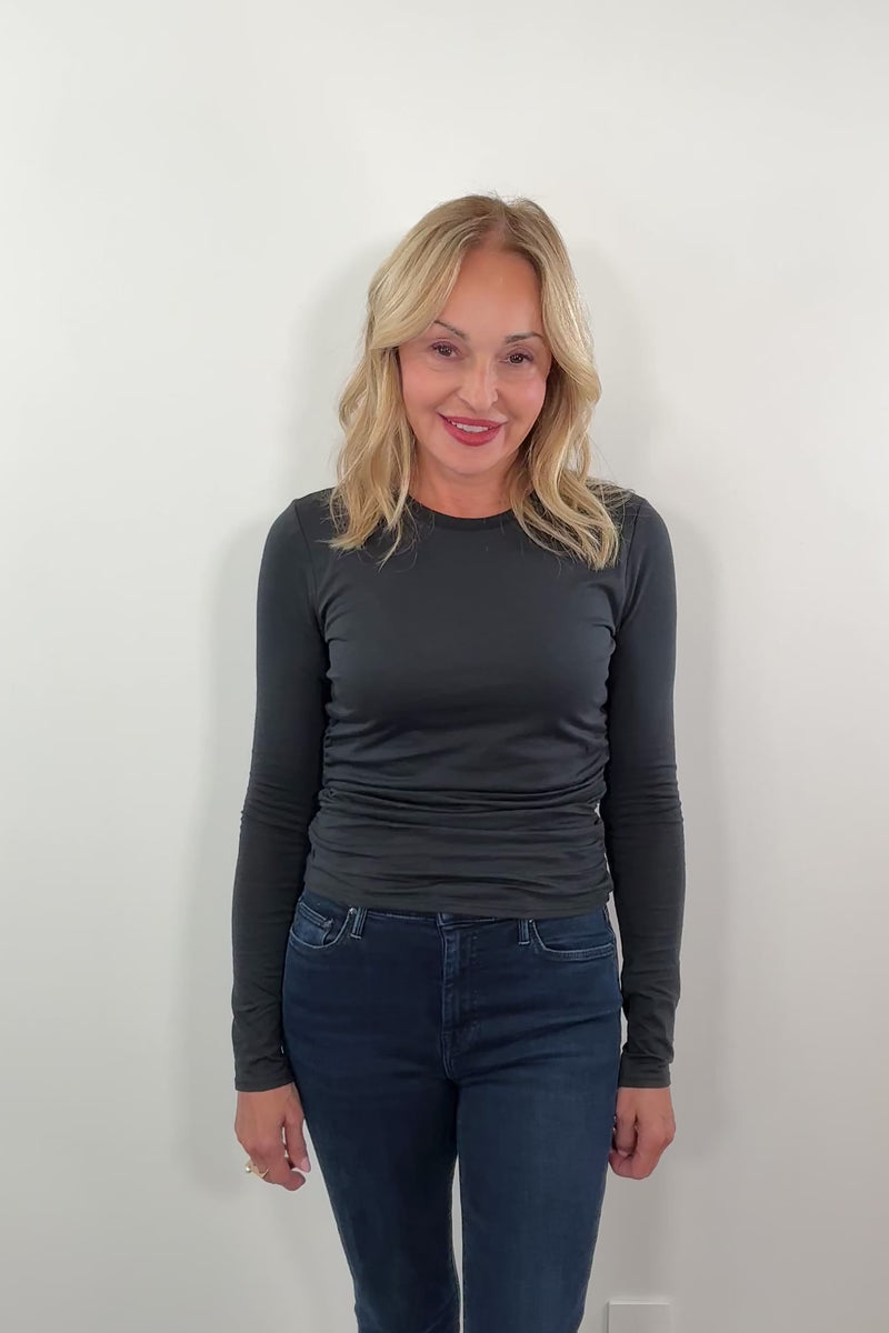 woman wearing a long sleeve black top with ruched detailing on the side