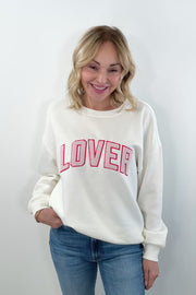 video of a woman wearing a off white crewneck with the word "LOVER"written in pink chenille