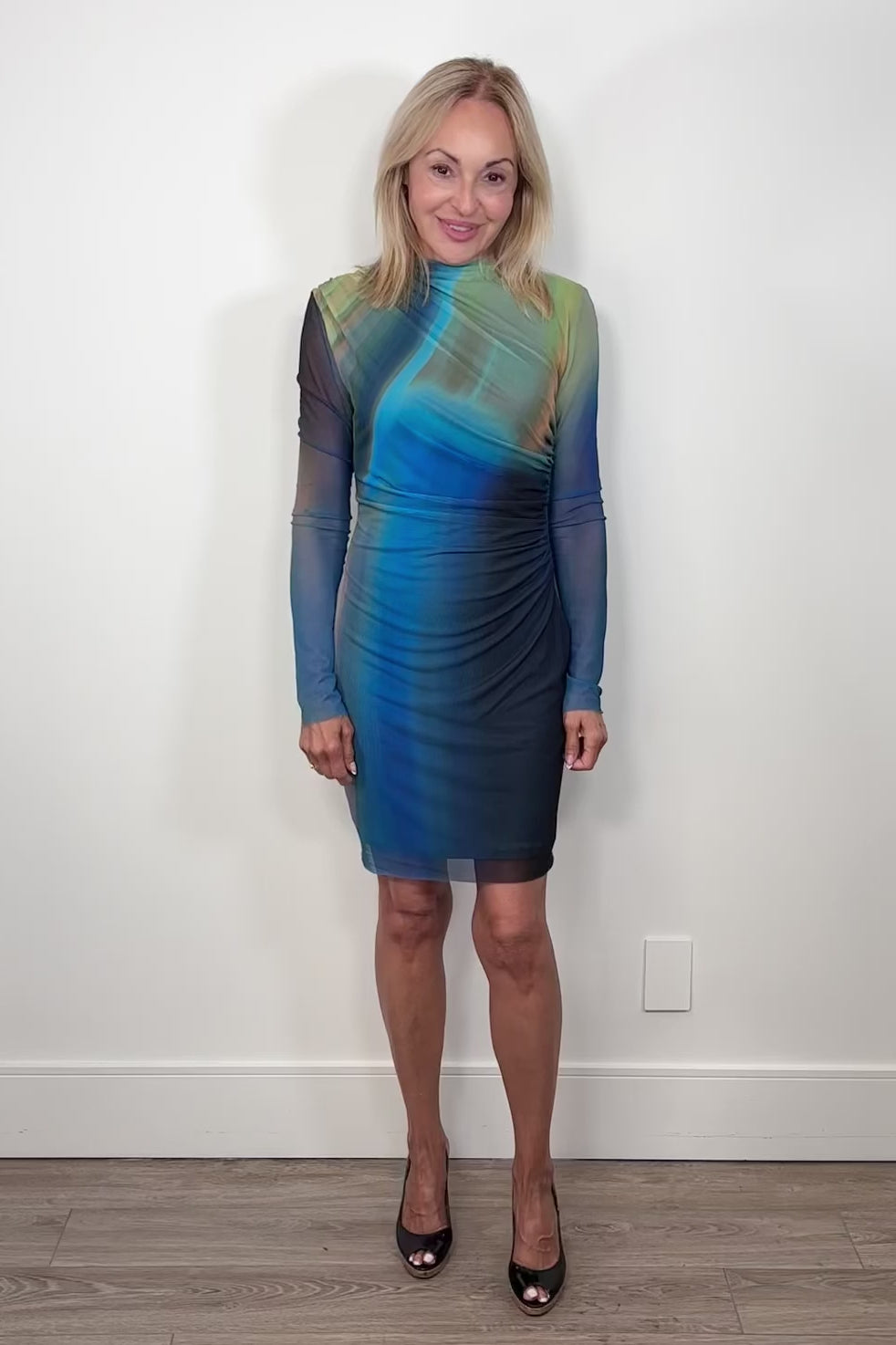 Video of woman wearing a blue and green dress with sheer sleeves on a white background