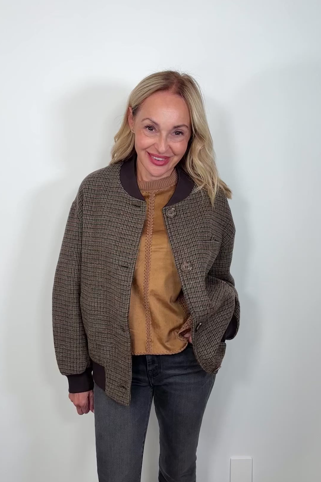 Video of a woman wearing a green-brown plaid bomber jacket
