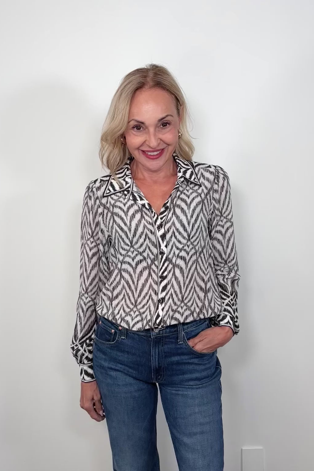Video of woman wearing a button up blouse with zig zag black stipes