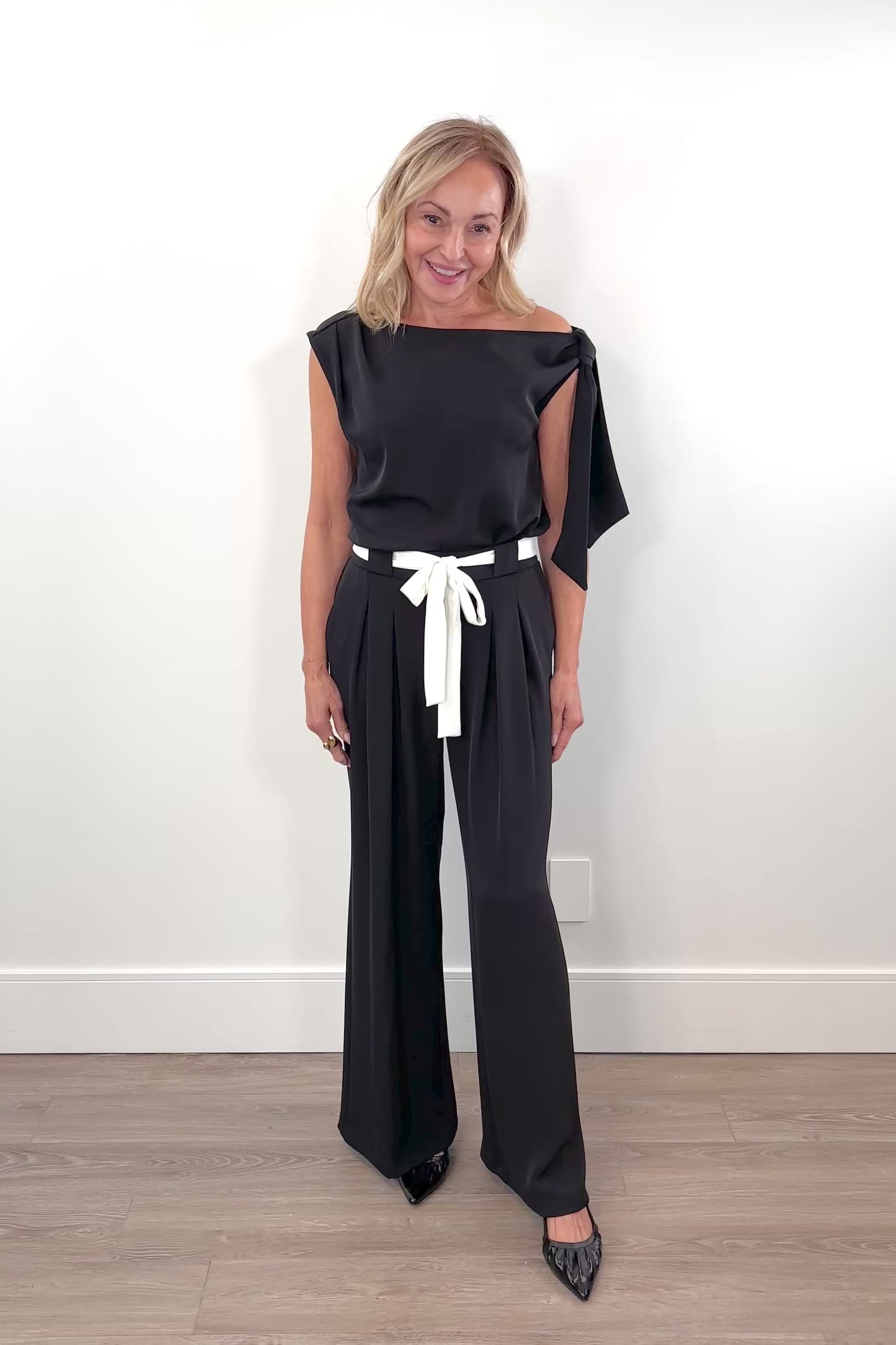 Video of woman wearing a black pat with white shash belt 