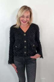 video of a woman wearing a black textured cardigan with silver buttons 