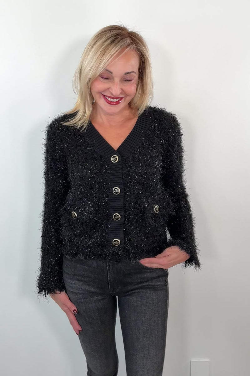 video of a woman wearing a black textured cardigan with silver buttons 