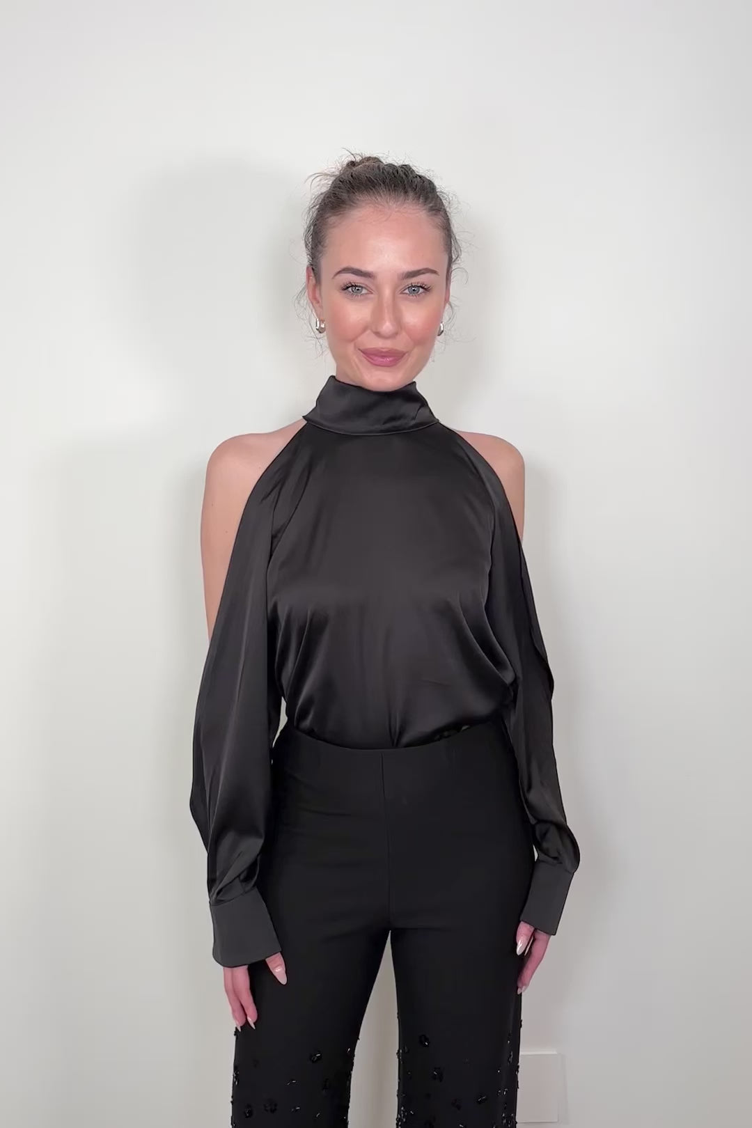 Video of woman wearing a black satin off-shoulder halter top 