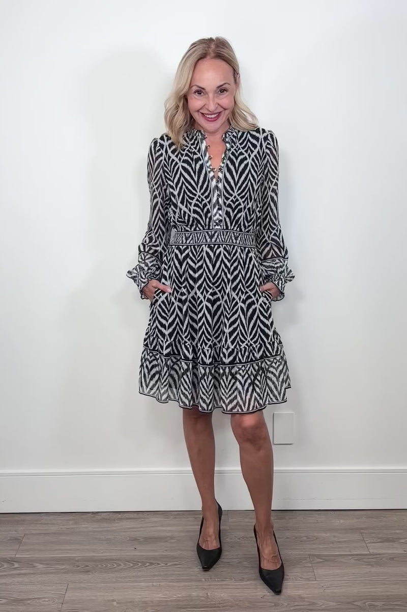 Video of woman wearing a dress with a smocked elastic waist and neckline with black and white stripes 