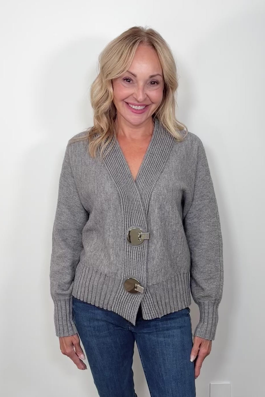 Video of woman wearing a gray cardigan with silver looking hardwear
