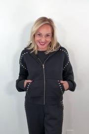 video of a woman wearing a black zip-up with studs along the seems