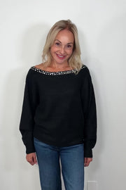 video of a woman wearing a black sweater with rhinestones in the neckline turning to show the garment
