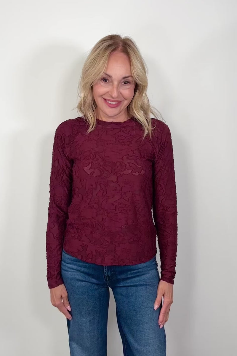 Video of a woman wearing a long sleeve burn out floral tee