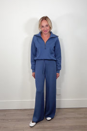 Woman wearing a washed blue zip-up sweatshirt against a light gray background on video