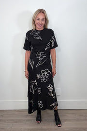 Video of woman wearing a black floral dress turning around to show the back