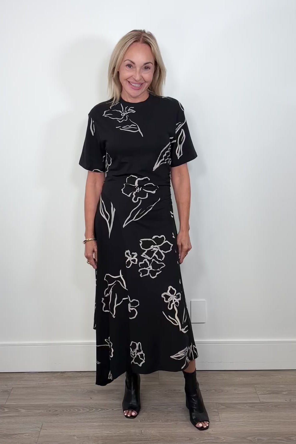 Video of woman wearing a black floral dress turning around to show the back