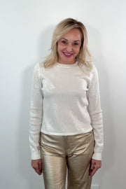 video of Woman wearing a white sequin top and gold pants against a plain background