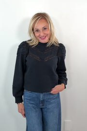 video of a woman wearing a black sweatshirt with lace detailing and cuffed poplin  sleeves